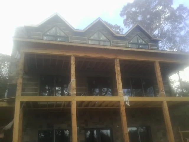 Dormers and porch framing on a large log home under construction — Roof Coating work by our crew in Eskridge