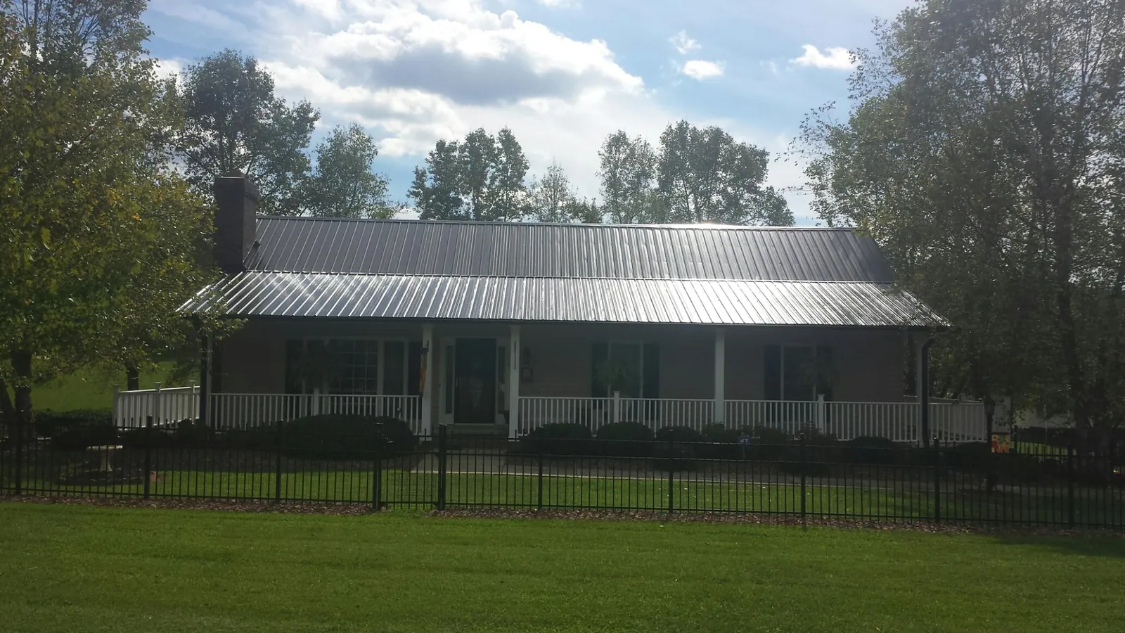 Gray metal roof on a brick ranch with a full width front porch — Gutter Guard Installation work by our crew in Eskridge