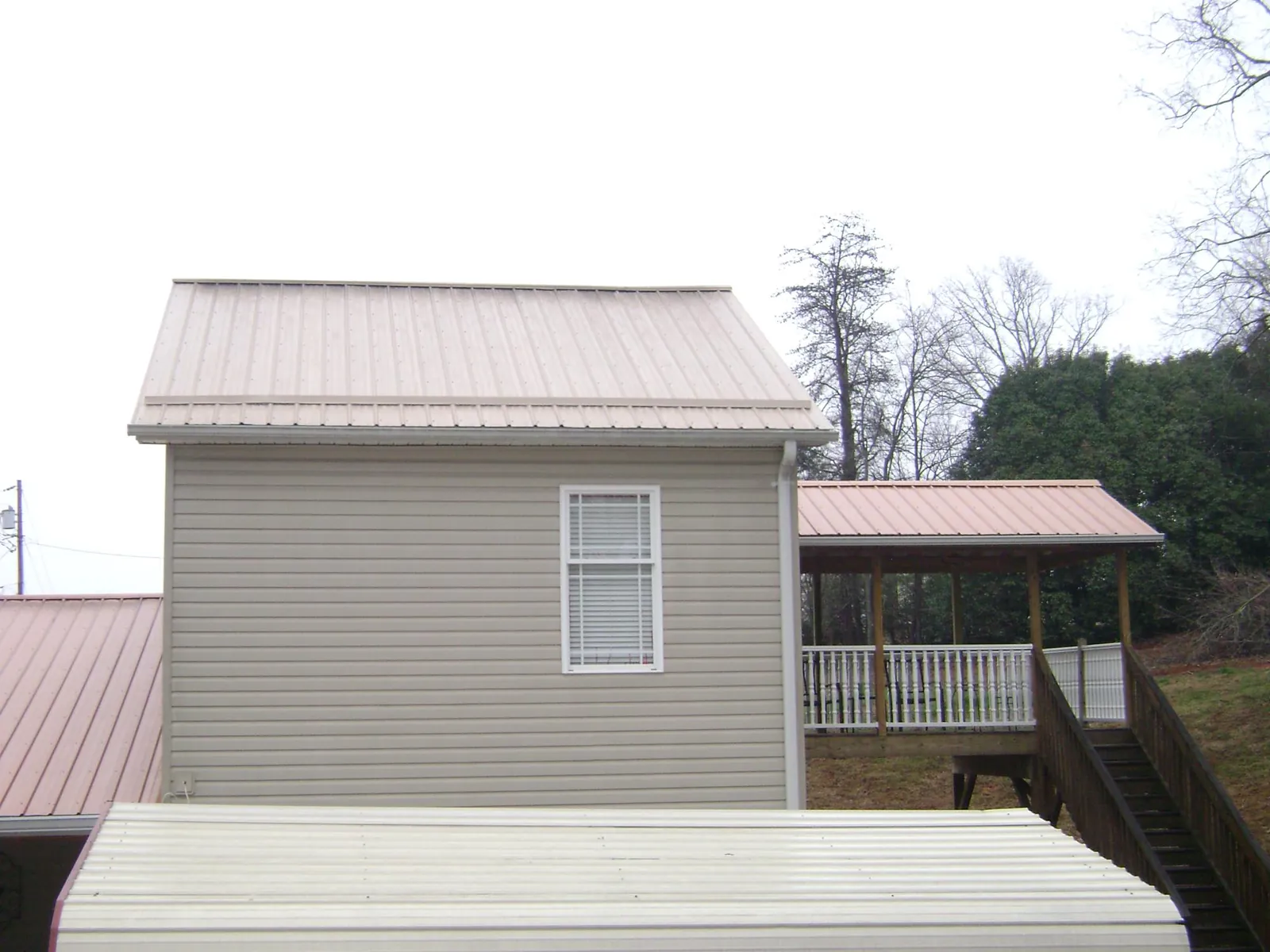 Tan metal roofs on a two story addition and attached porch, from a Roof Replacement job in Eskridge