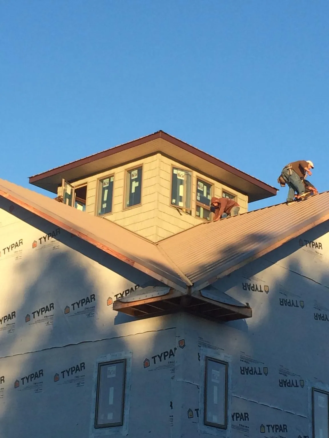 Roofers working around a rooftop cupola on a new metal roof at sunset — Roof Waterproofing in Eskridge by Roofing Brothers